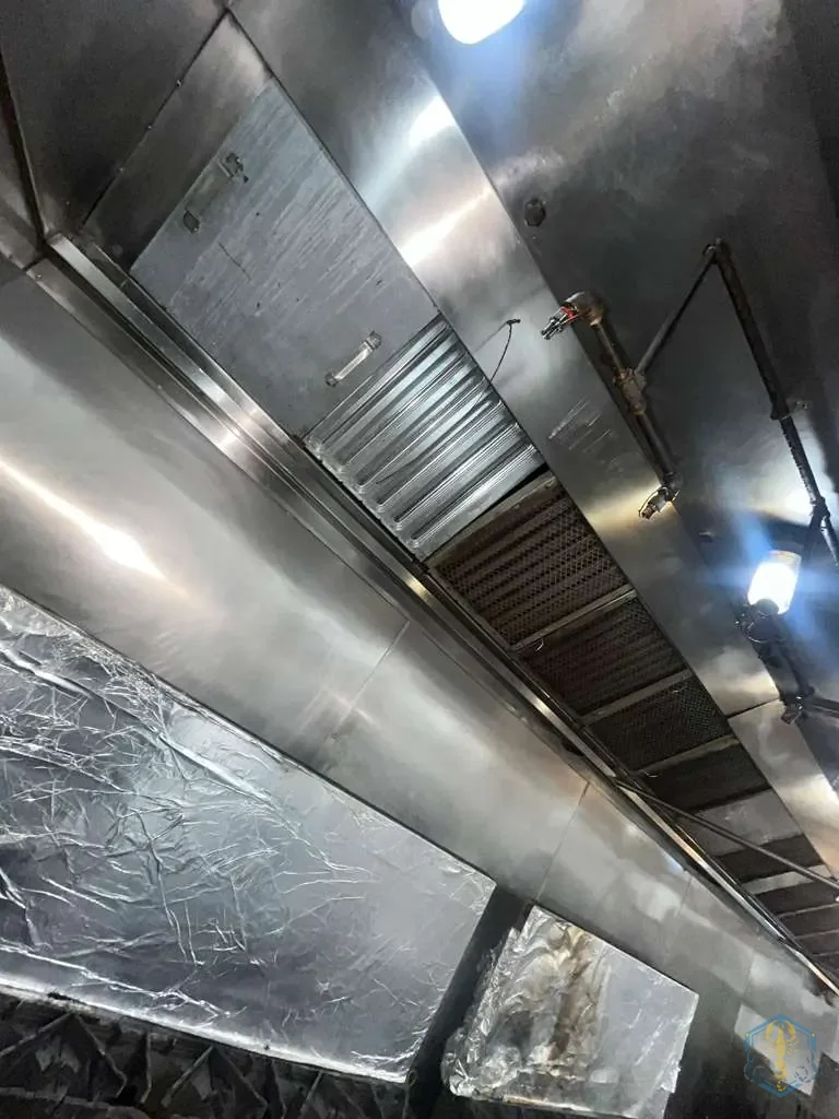 Hood interior after cleaning, with containment sheeting still in place and the surfaces washed to bare metal.